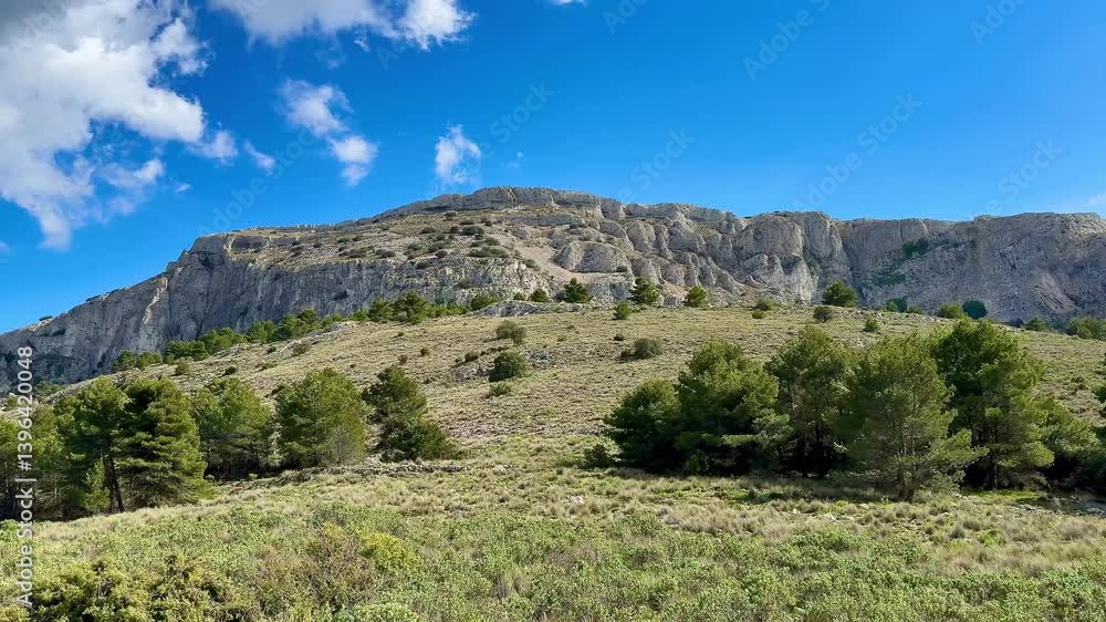 A captivating view of a majestic mountain range surrounded by lush greenery beneath a clear blue sky above A captivating view of a majestic mountain range surrounded by lush greenery beneath a clear blue sky above