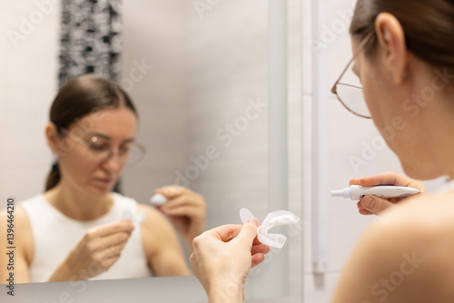 Woman preparing silicon tray for teeth whitening and bleaching gel syringe. Themes dental health, care and beauty. 