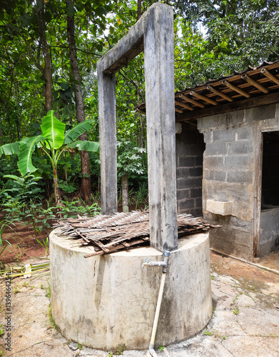 A traditional village bathroom setup featuring a manual well and two separate rooms. one for bathing and the other for toilet use