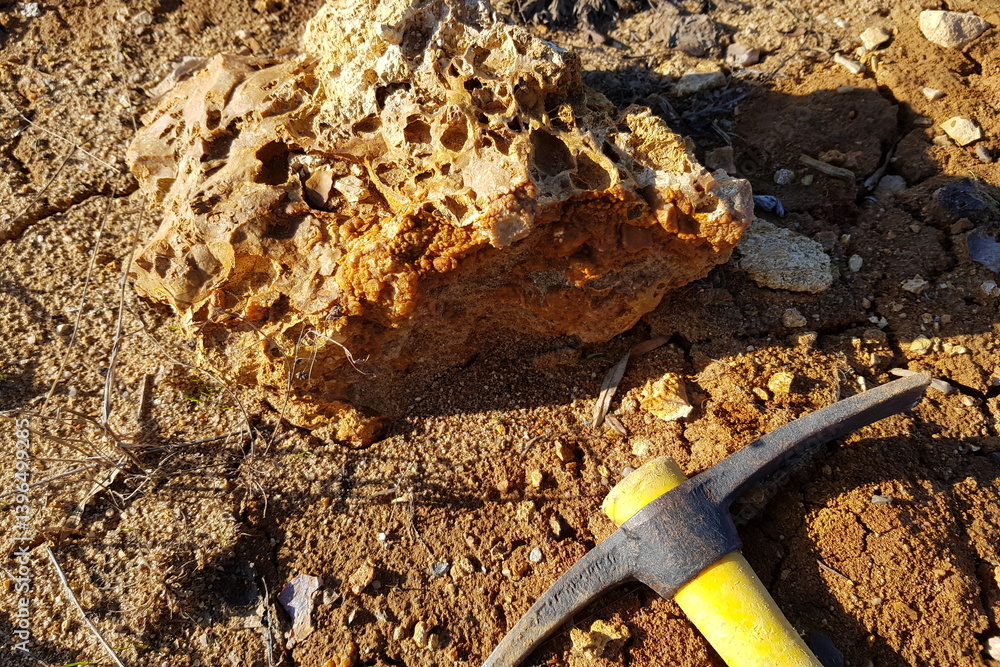 Search for mineralogical samples at a quarry, a pickaxe lying next to a siliceous rock Search for mineralogical samples at a quarry, a pickaxe lying next to a siliceous rock