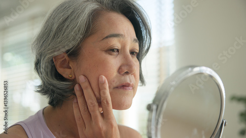 Foto Asia adult people middle age old woman look at mirror dry skin face hand touch neck cheek stress sad at home elder health care aging beauty issue