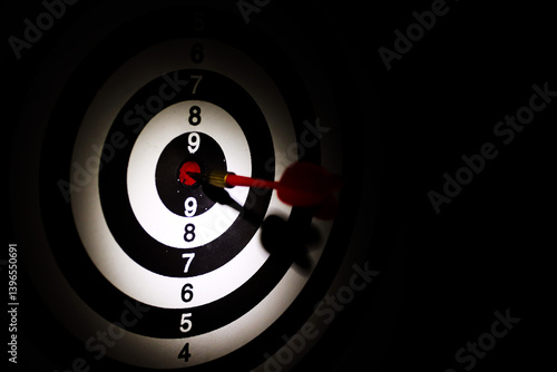 Dart arrow hitting in the target center of dartboard,Arrow on a black background