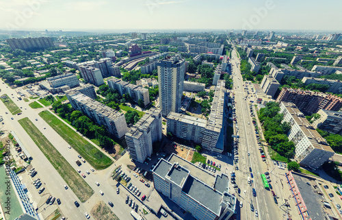 Aerial city view with crossroads and roads, houses, buildings, parks and parking lots, bridges. Urban landscape. Copter shot. Panoramic image.