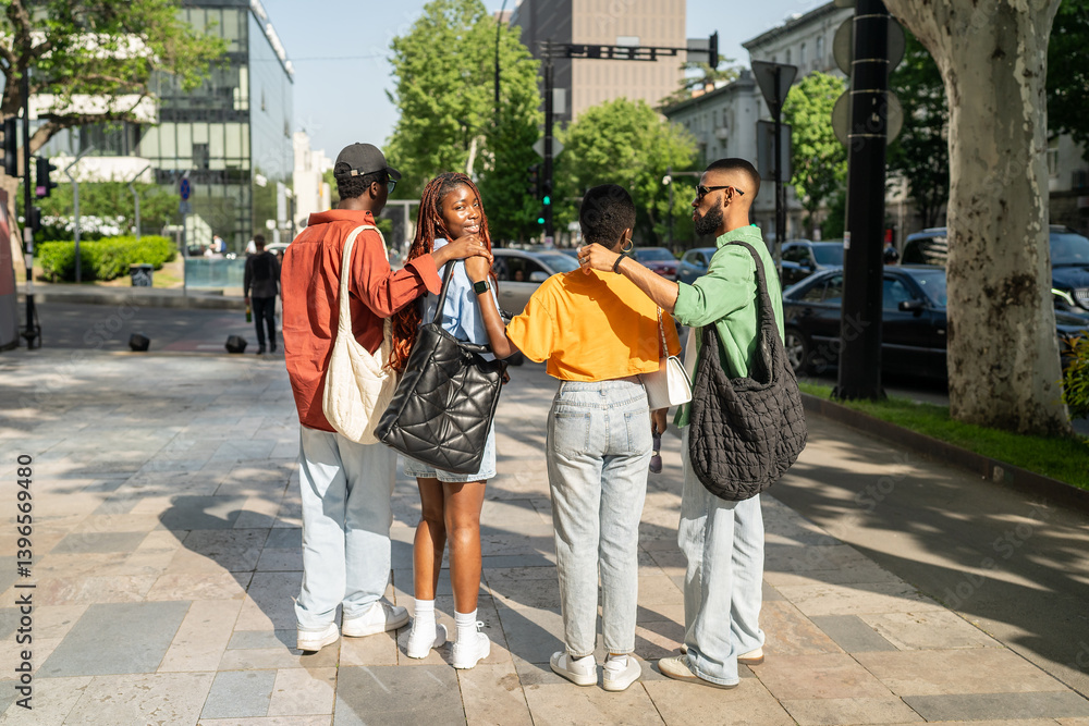 Fototapeta premium Rear view of Black African American friends company hugging, spinning toward camera laughing. City streets adventure, generation Z leisure activity, multicultural friendship, spontaneous fun plans
