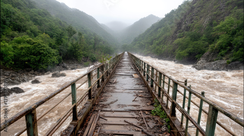 damaged bridge stretches over raging river amid lush green mountains