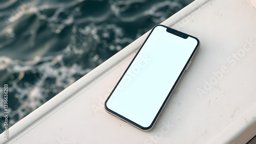 A smartphone with a blank screen lying on a boat deck with the sea in the background.