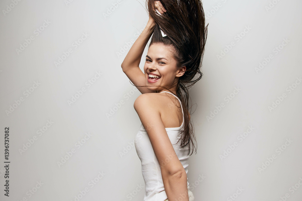 Happy young woman expressing joy, dancing with her hair in motion, against a plain light background, showcasing a carefree and vibrant mood, symbolizing happiness and freedom Happy young woman expressing joy, dancing with her hair in motion, against a plain light background, showcasing a carefree and vibrant mood, symbolizing happiness and freedom