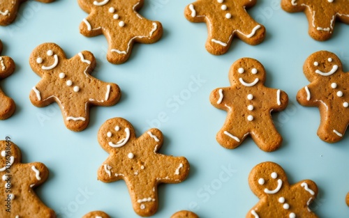 An assortment of cheerful gingerbread cookies, decorated with icing and white dots, on a light blue background