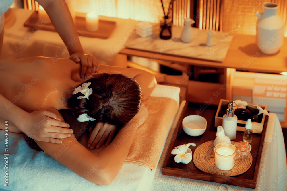 Caucasian woman customer enjoying relaxing anti-stress spa massage and pampering with beauty skin recreation leisure in warm candle lighting ambient salon spa at luxury resort or hotel. Quiescent