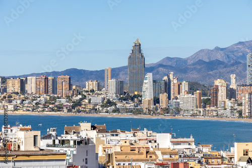 Obraz na płótnie Aerial drone photo over looking the old town of Benidorm in Spain showing apartments and high rise buildings on the Poniente Beach front with the ocean and mountains in the background on a sunny day w salonie