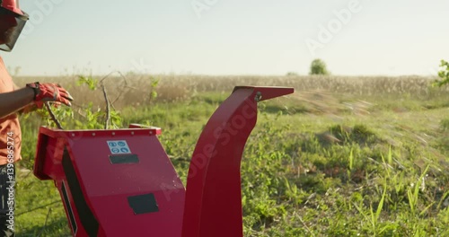 Garden worker using wood chipper shredder machine to make branch mulch