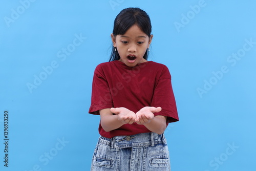 Wow and amazed expression of asian little girl while holding something on her hands