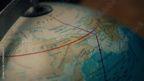 Close up of a globe map slowly rotating towards East, following the arctic circle above Yukon, Alaska, Bering strait and Siberia. 4K