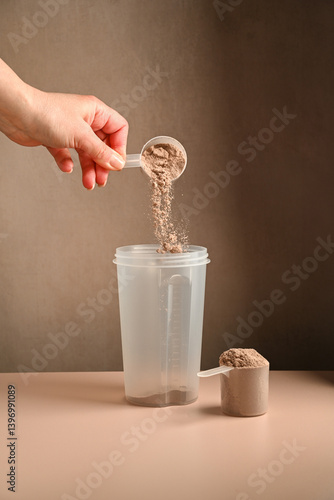 Making protein drink. Pouring chocolate protein powder in a shaker, food supplement concept