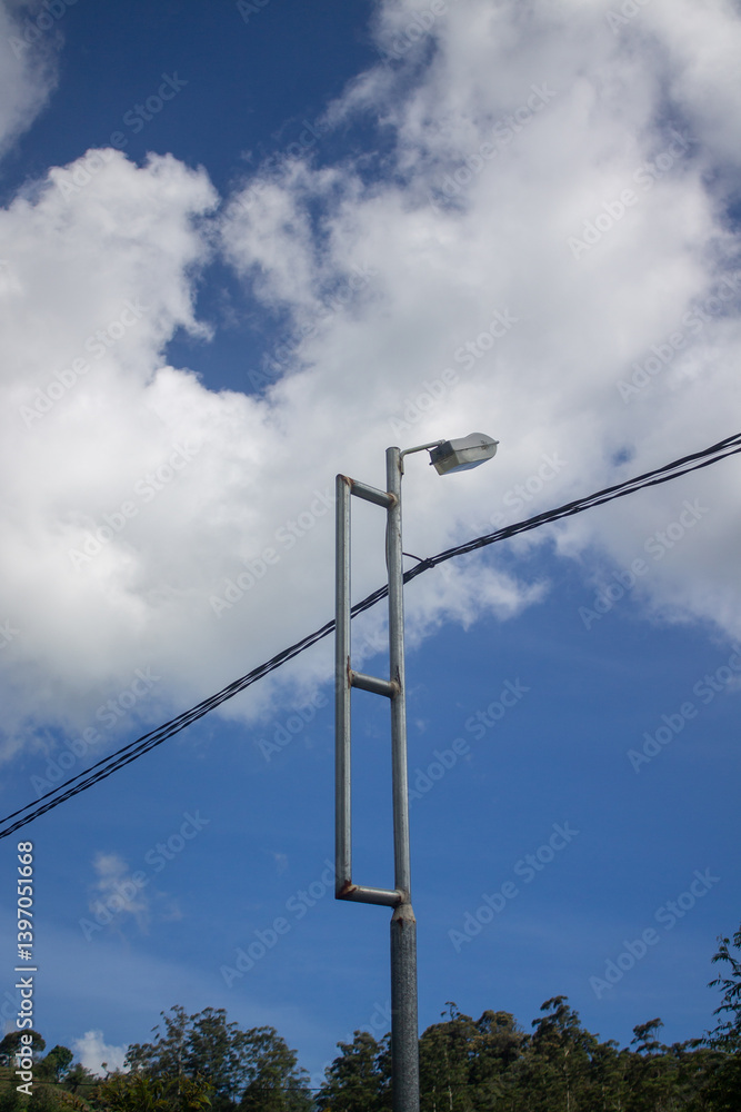 The street lamp poles stood firmly under the bright blue sky and white clouds. The street lamp poles stood firmly under the bright blue sky and white clouds.