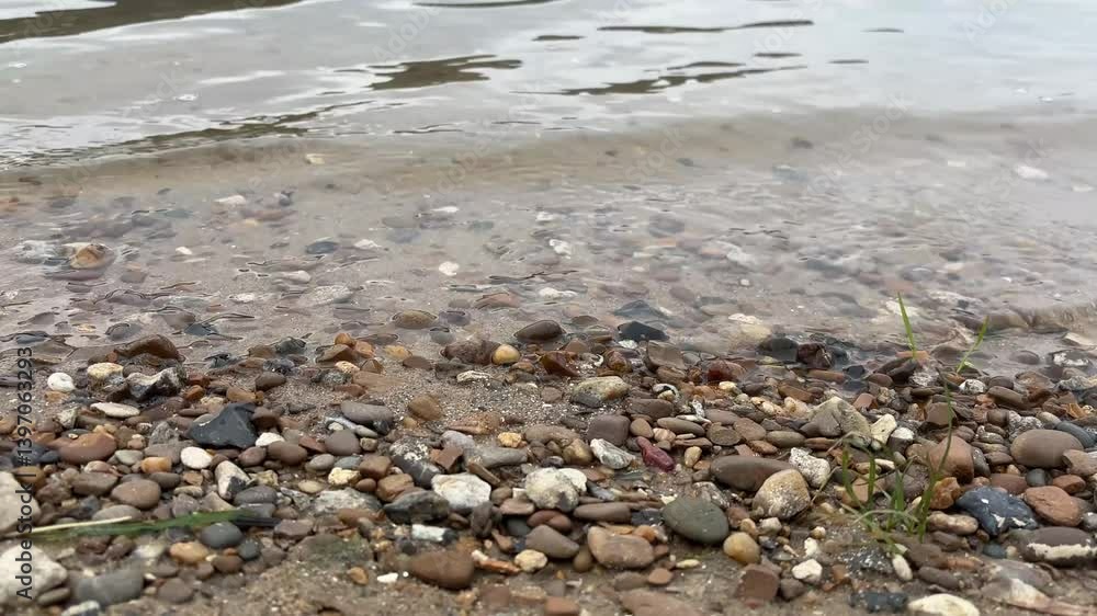 The Dniester River. Waves on the river in spring. A reservoir in the cold season. A beach with stones on the river bank The Dniester River. Waves on the river in spring. A reservoir in the cold season. A beach with stones on the river bank