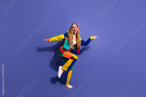 Obraz na płótnie Young woman celebrating and smiling in vibrant, colorful casual outfit, over purple background, expressing happiness w salonie