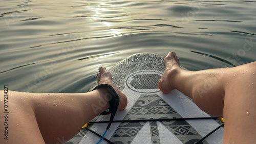 Fototapeta Naklejka Na Ścianę i Meble -  Person relaxing on paddle board enjoying sunset on water surface