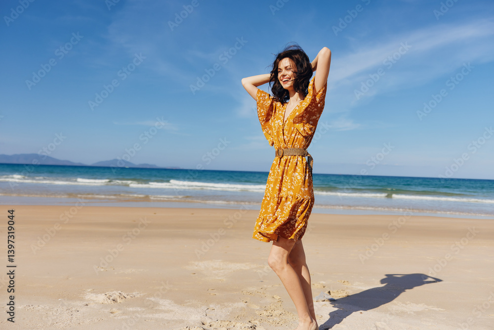 Calm woman in a vibrant yellow dress standing confidently on the sandy beach with hands on hips Calm woman in a vibrant yellow dress standing confidently on the sandy beach with hands on hips