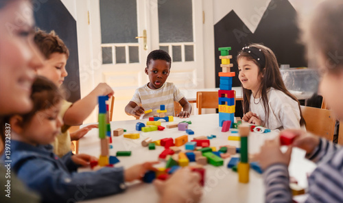 Obraz na plátně Group of diverse preschool children playing with colorful building blocks at a table in a bright, organized kindergarten classroom