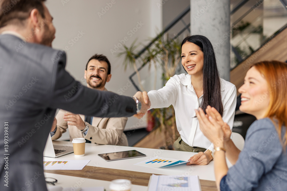 Friendly businesswoman having handshake with team member in boardroom.
