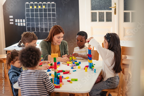 Quadro su tela Diverse preschool children play with colorful building blocks at a classroom table, guided by a smiling teacher in a creative, inclusive early learning environment
