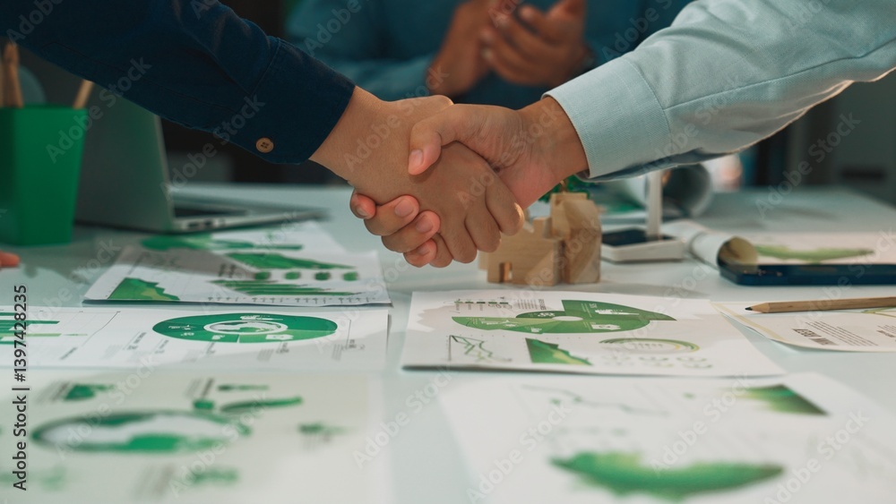Fototapeta premium A close-up of hands shaking over business strategy documents featuring graphs and charts, symbolizing collaboration and agreement in a professional setting. SACTR