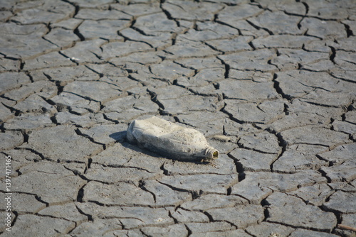 Plastic bottle on dry cracked earth in an arid area highlighting environmental pollution and drought conditions