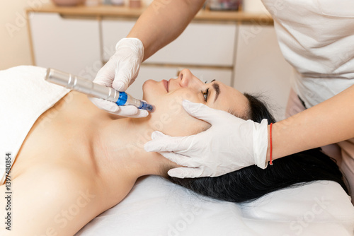 Cosmetologist doing microneedling, patient care using dermapen in a beauty salon