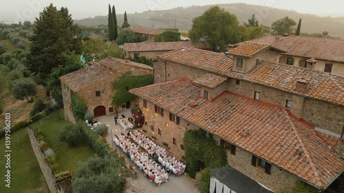 Drone shot of an outdoor wedding dinner in Tuscany, Italy near a villa with long tables, general plan with the villa Quercia al Poggio