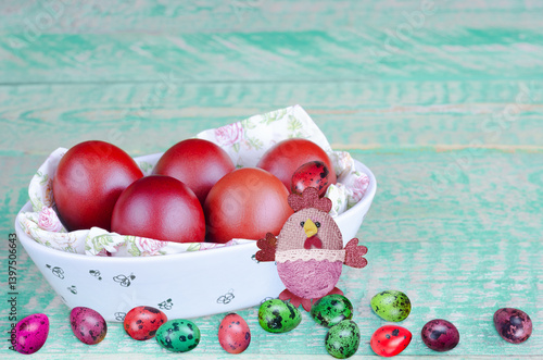 Painted Easter eggs in a bowl, and on an old wooden table. Selective focus