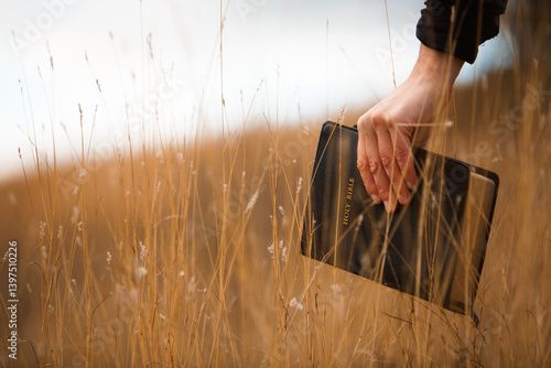 Man holding a bible against the background of a field and sky