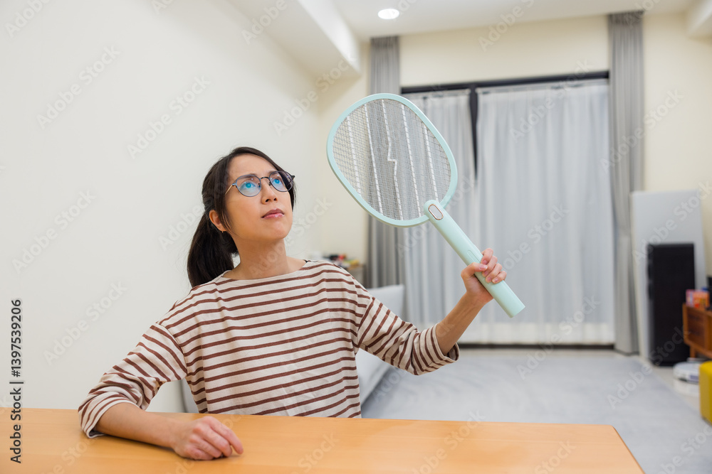 Woman using electric mosquito swatter to kill mosquito Woman using electric mosquito swatter to kill mosquito