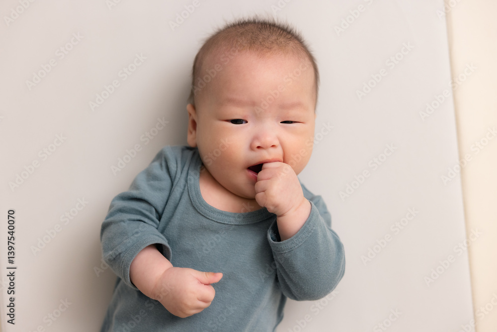 Cute newborn baby sucking tiny fingers