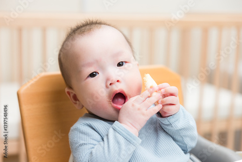 Obraz na płótnie Infant eating biscuit while sitting in chair w salonie