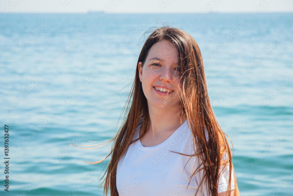 Smiling young woman enjoying a sunny day at the beach by the ocean. Happy summer days, travel and vacation concept Smiling young woman enjoying a sunny day at the beach by the ocean. Happy summer days, travel and vacation concept