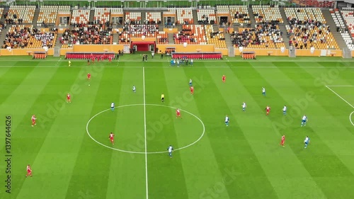 Football match with teams teams dressed in red and blue are engaged in a thrilling football match at a vibrant stadium. Fans cheer enthusiastically as players strategically maneuver for a goal