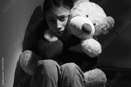 Obraz na płótnie Conceptual image: Emotional and behavioral problems of adolescents. Lonely and sad teenage girl hugging her only friend, a Teddy bear toy. Black and white portrait. w salonie