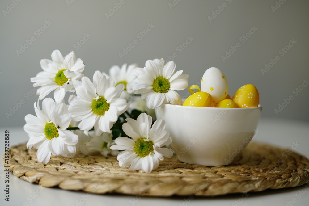 White bowl with yellow Easter eggs and daisies on woven placemat White bowl with yellow Easter eggs and daisies on woven placemat