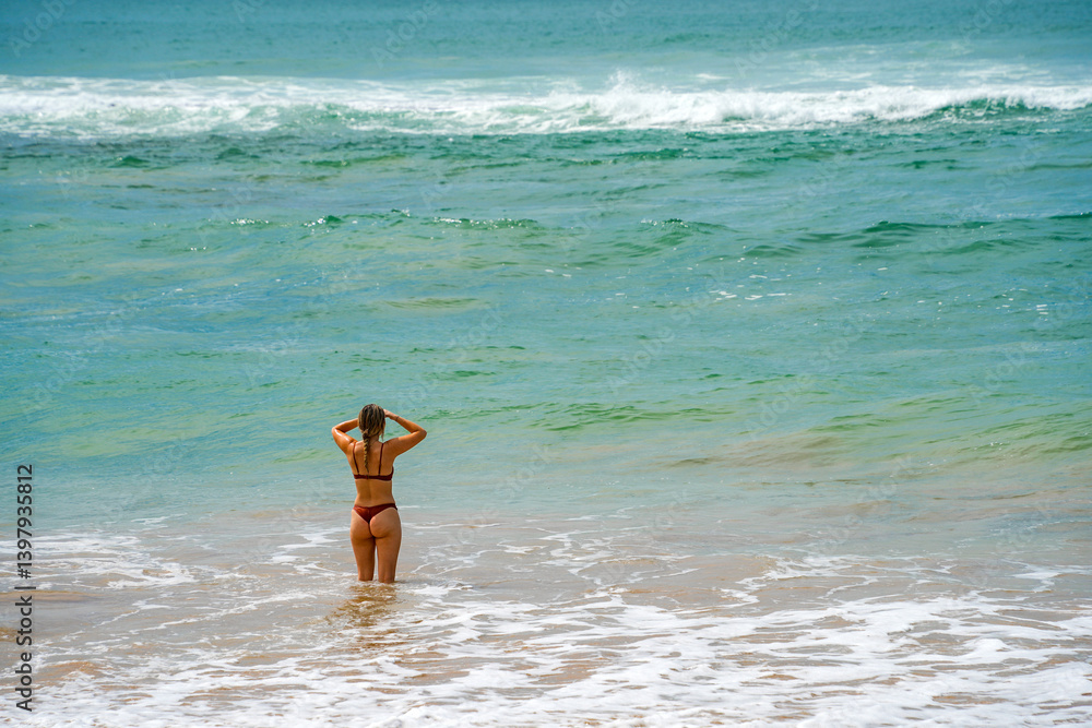 Beautiful young girl enjoying the waves of the ocean