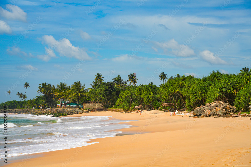 Koggala beach with blue cloudy sky and foamy waves, Koggala, Sri Lanka,