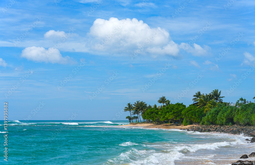 Koggala beach with blue cloudy sky and foamy waves, Koggala, Sri Lanka,