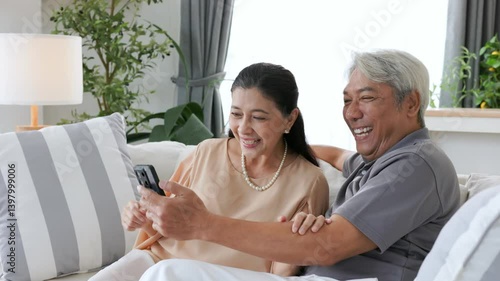 Senior couple using phone to watch their favorite team play football.