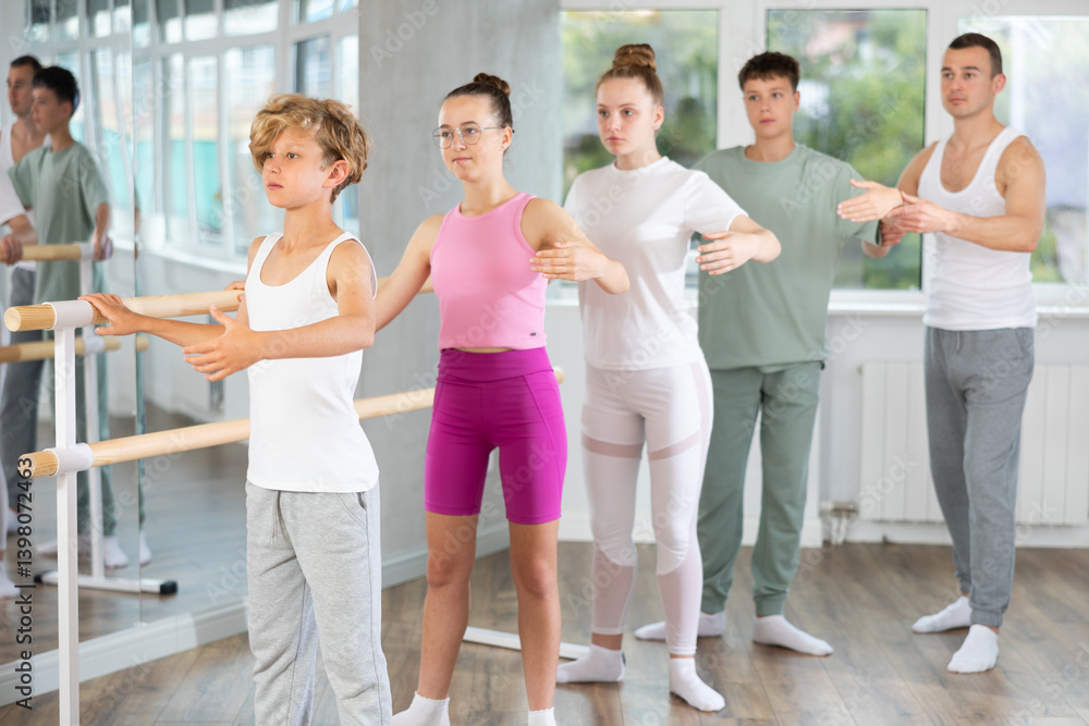 Obraz premium Group of teenagers practice ballet moves in classical dance school