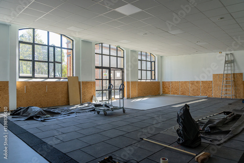 Salle de classe en cours de rénovation dans une école, avec matériel de chantier et murs partiellement refaits.