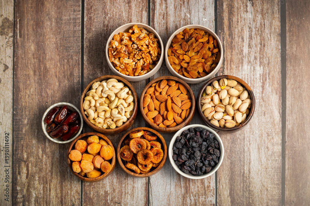 an assortment of dried fruits and nuts arranged in bowls on a white wooden surface, including dates, cashews, almonds, raisins, figs, apricots, and walnuts. an assortment of dried fruits and nuts arranged in bowls on a white wooden surface, including dates, cashews, almonds, raisins, figs, apricots, and walnuts.