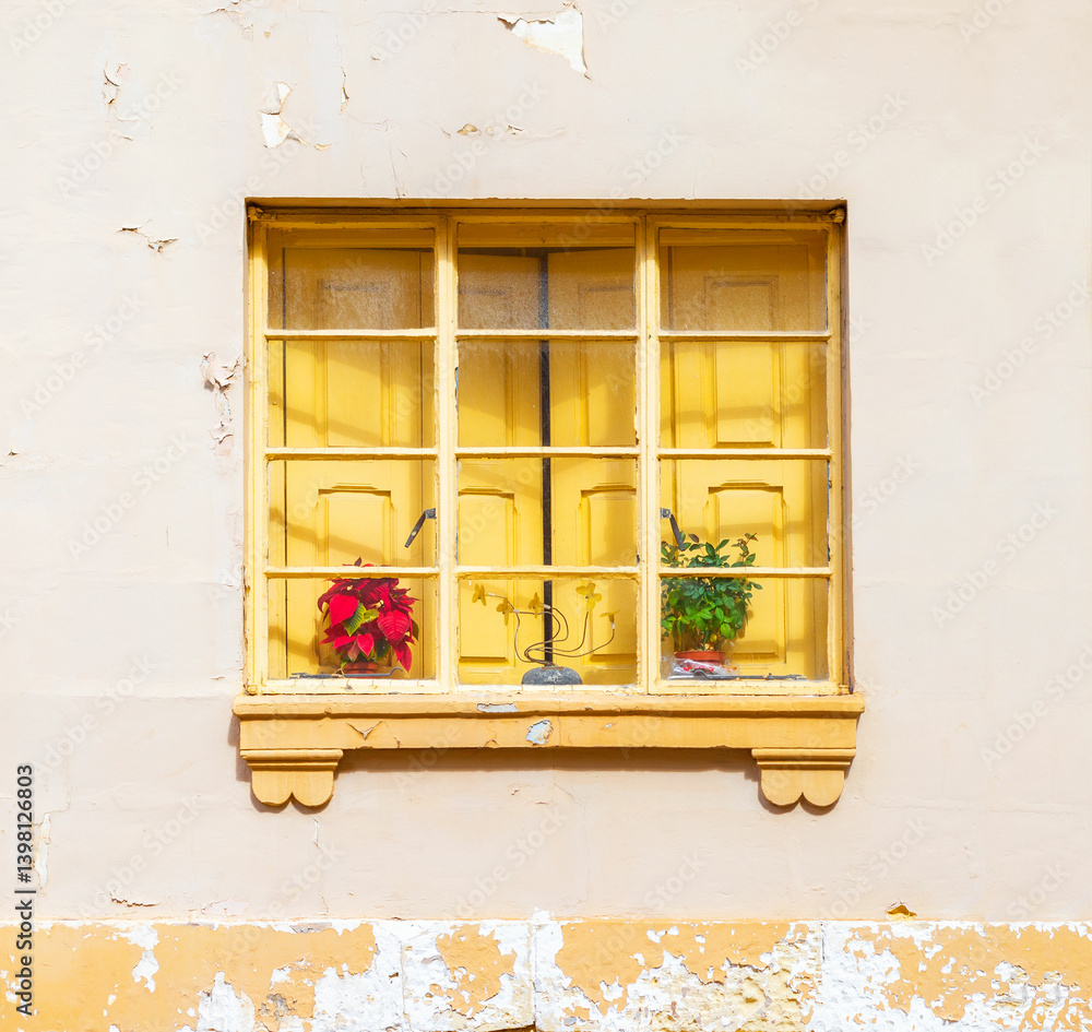 A yellow window with closed shutters behinde the frame