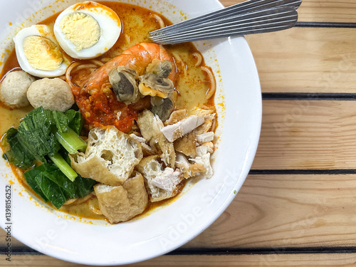 Photography A bowl of curry noodles on wooden table.  Top view.