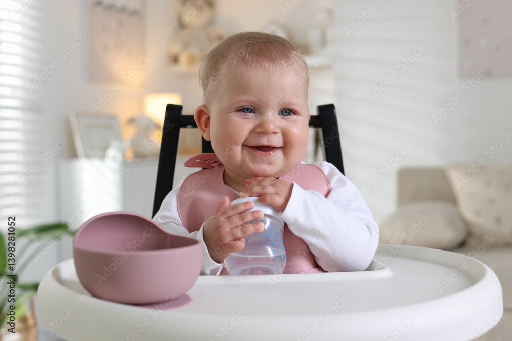 Cute little baby with bottle on feeding chair at home