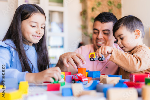 Happy father and children building with construction toys and toy cars, enjoying family time together